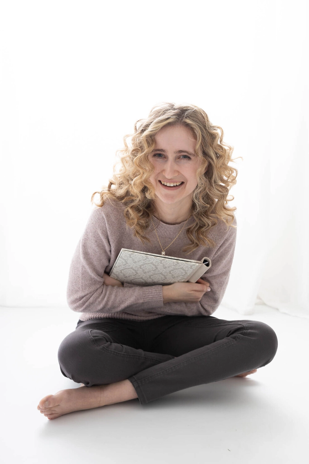 Jasmin sitzt mit ihren Planer am boden und lächelt in die Kamera