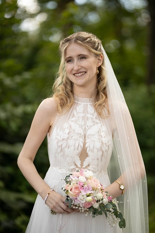 Jasmin mit ihrem Brautkleid und dem Brautstraus in der Hand