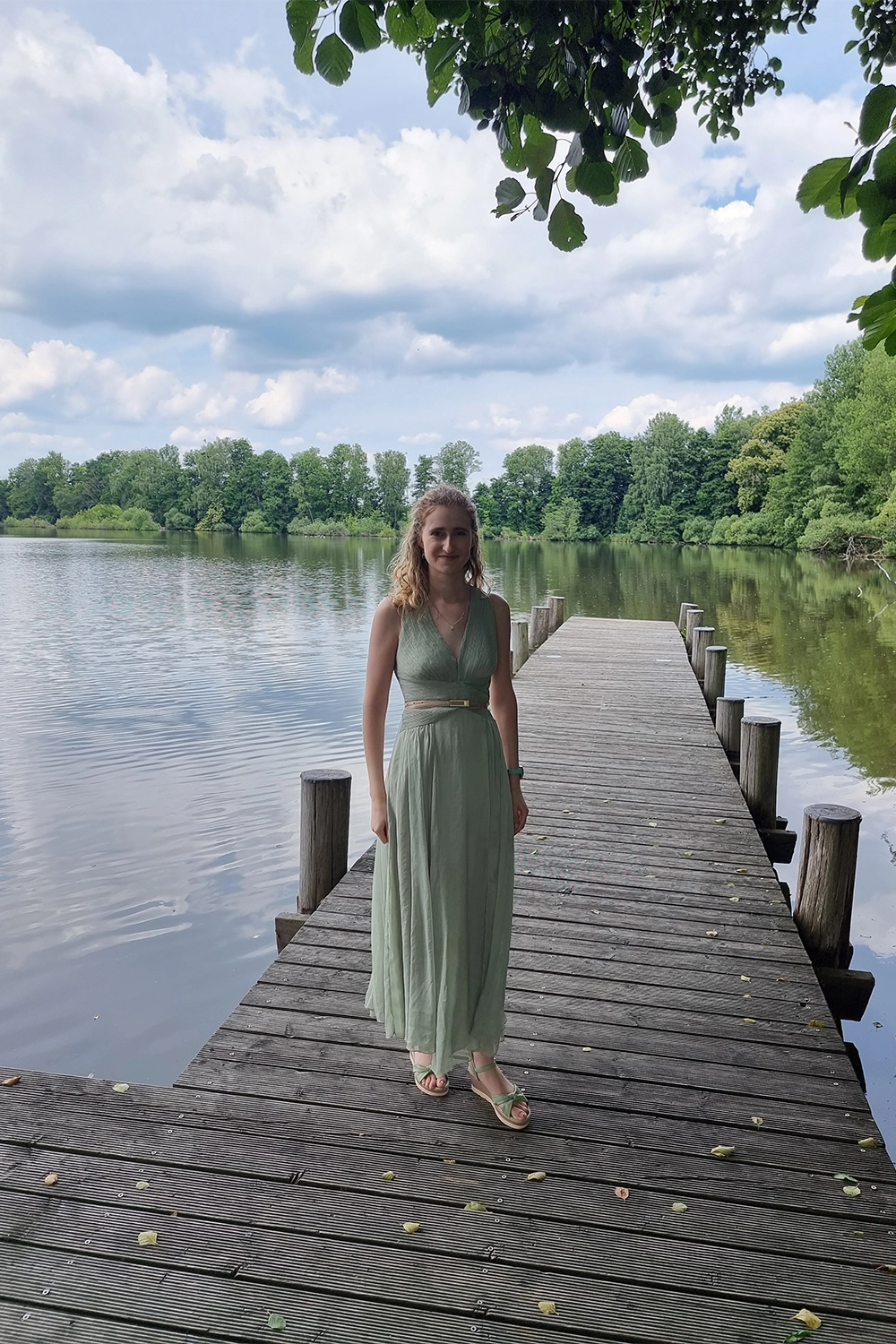 Jasmin steht auf einem Pier mit Blick auf einen See.