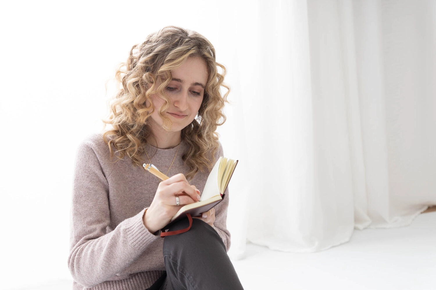 Jasmin sitzt am Boden und schreibt in ihren Planer